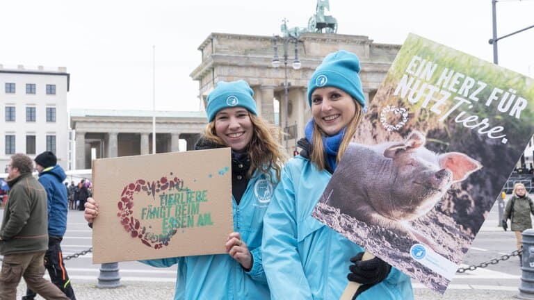 Zwei junge Frauen mit Demo-Plakaten vor dem Brandenburger Tor in Berlin.