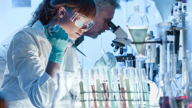 Forschender Mensch arbeitet in einem Labor mit Reagenzglaesern.